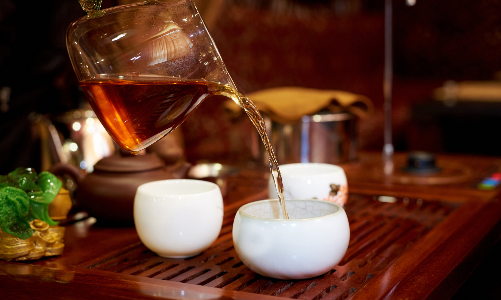 Gong fu tea a clear tea pot pouring into white tea cups