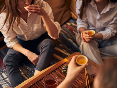 A group of women holding and sipping tea from an overhead angle discussing the history of tea