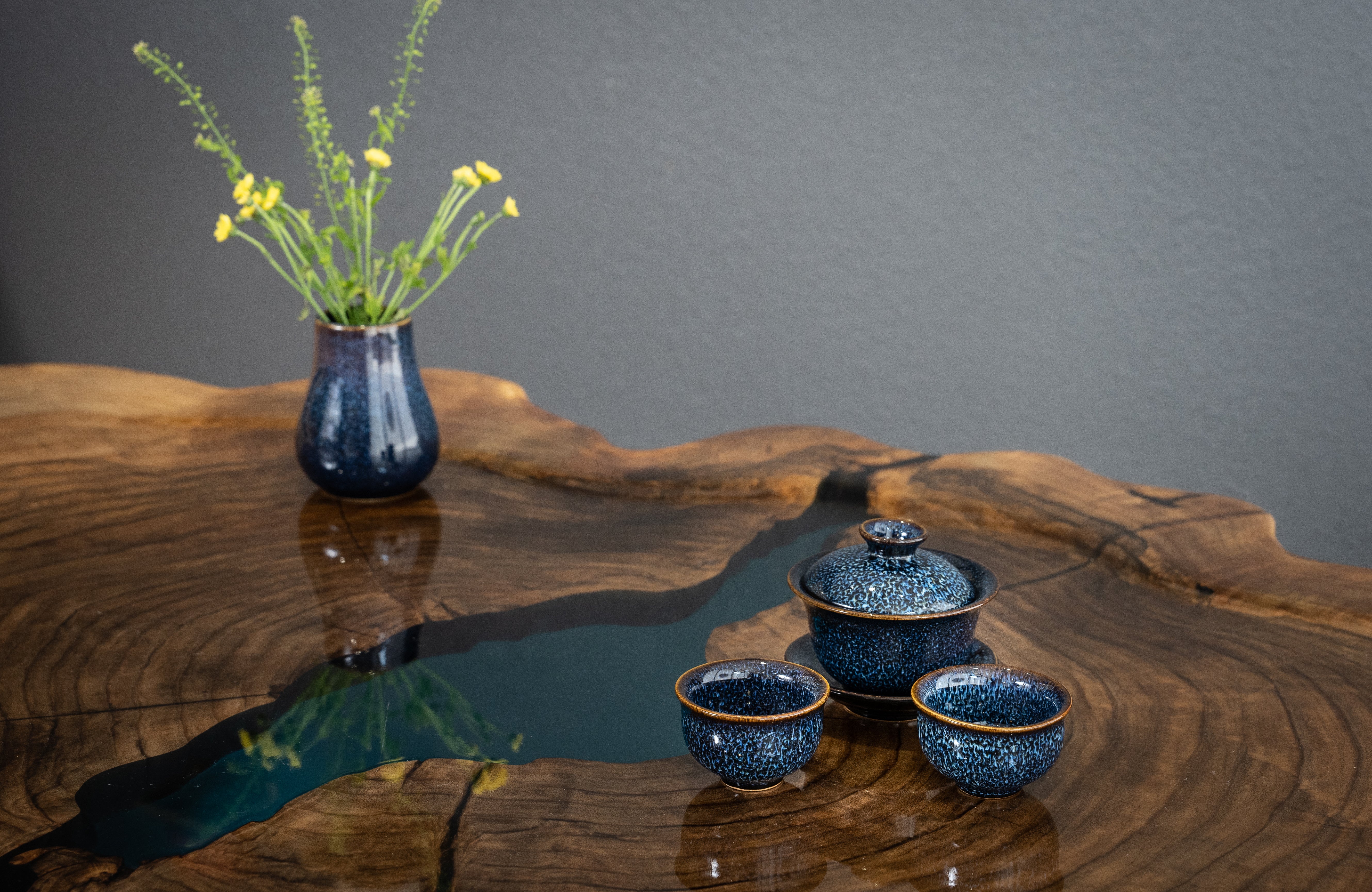 Blue gaiwan set and flower arrangement sitting on beautiful tea table.